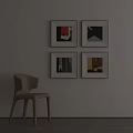 Four Abstract Paintings on White Wall with Beige Chair in Room