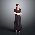 A Woman in Black Long Dress Standing with Arms Crossed Against Gray Background