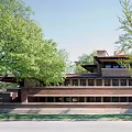 Red Brick Single Family Home With Black Roof Large Windows Surrounding Trees And Green Lawn