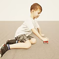 Little Boy Wearing White T-Shirt and Plaid Shorts Playing with Red Toy Car on Floor