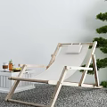 Wooden Frame Lounge Chair With White Cushion Side Table And Green Tree On Gravel Ground