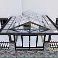 Modern Glass Roof Garden Pavilion with Transparent Geometric Structure and Stone Wall Railing