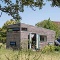 Wooden Detached Villa With Covered Porch Green Door And Grass Surrounding Trees