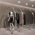 Modern Circular Display Rack With Metallic Frame Hanging Clothes And Mannequin Against Gray Wall