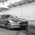 Silver Sports Car Parked In Indoor Space With White Walls Metal Roof And Tire Tracks