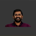 Man with short black hair and beard wearing purple striped polo shirt against gray background
