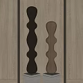 Two Carved Columnar Sculptures With Curved Design In Different Materials Against Light Wood Wall Background