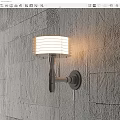 Modern Wall Sconce With White Striped Lampshade Emitting Warm Light On Textured Wall