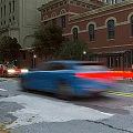 Vibrant Commercial Street Featuring Red Brick Buildings Arched Windows Street Trees And Moving Cars