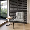 Textured Gray Lounge Chair with Small Round Table Black Louvered Shutters and Greenery View