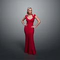 Woman in Red Long Dress Standing with Hands on Hips Against Gray Background