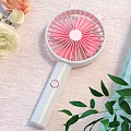 Portable Handheld Fan With Pink Blades And White Handle Near Green Leaves And Flowers