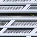 Modern High Rise Building With Geometric Facade And Greenery In Urban Area