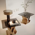 Modern Glass Top Side Table With Golden X Shaped Base And Decorative Plant