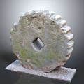 Ancient Mossy Stone Gear Artifact With Square Hole And Toothed Edges On Gravel Base