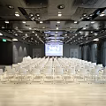 Spacious Modern Conference Room With White Chairs Front Projection Screen Ceiling Lights And Wooden Floor