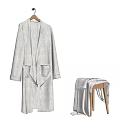 Soft White Long Robe Hanging On Wooden Hanger With Folded Towel On Stool