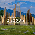 Scenic Wall With Wooden Mountain Shaped Vertical Slats Against Blue Sky Mountain Backdrop And Lawn