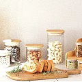 Glass Spice Jars with Wooden Lids and Nuts Bread Slices on White Kitchen Counter