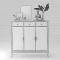 White Shoe Cabinet With Golden Handles Drawers And Decorative Items On Top