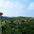 Detached Villa Surrounded by Lush Green Trees With Distant Mountains Under Blue Sky and White Clouds