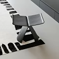 Modern Black Leather Stool On Black And White Patterned Rug In Interior