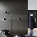 Woman in dark coat with blurry back near black floor lamp and grey striped wall