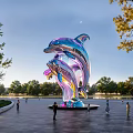 Vibrant Metallic Dolphin Landscape Sculpture In Park With People Around