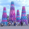 Colorful Geometric Illuminated Towers Stand At Night With People Gathering Around