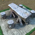 Rustic Outdoor Table With Four Stump Stools On Wooden Pattern Mat With Green Edges