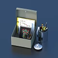 Open Gray Box With Notebook Colorful Pens Metal Pen Holder And Magnifying Glass