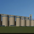 Industrial Plant Featuring Large Silos Green Lawn And Blue Sky With White Clouds