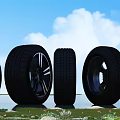 Different Car Tires With Rims Displayed Outdoors On Green Grass Under Blue Sky