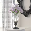 Transparent Glass Vase With Purple Roses Against White Patterned Curtain And Black Carved Mirror