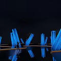 Blue Glowing V Shaped Art Installation In Dark Environment With Reflective Floor And Human Figure