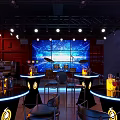 Modern Bar Interior With Blue Lit Backdrop Round Counters Black Chairs Neon Accents
