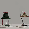 Green Bell Lamp With Red Bow And Beige Curved Lamp With Open Book Glass Saucer