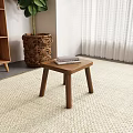 Black Wooden Stool Placed On Woven Rug Near Wicker Basket And Wooden Shelf In Interior