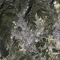 Satellite View of City Surrounded by Green Mountains and River With Residential Industrial Zones