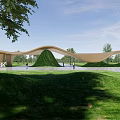 Modern Curved Entrance Gate Design In Demonstration Area With Green Lawn Plaza And Visitors