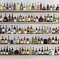 Wine Bottles and Glasses Collection Arranged on Multiple Wooden Shelves with Various Labels