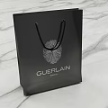 Stylish Guerlain Black Shopping Bag With Floral Pattern On Marble Surface