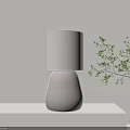Modern Table Lamp with White Lampshade and Dark Base on Light Tabletop with Green Plant