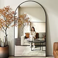 Large Arched Mirror Reflecting Cozy Living Room With Sofa Pillows And Decorative Tree