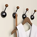 Wall Mounted Hooks With Black Base And Wooden Knobs Near Wooden Hanger Holding White Garment