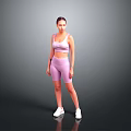 A woman wearing pink sports bra and shorts with white sneakers against gray background