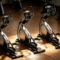 Three Elliptical Fitness Machines with Digital Displays on Wooden Gym Floor