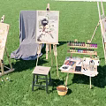 Artistic Outdoor Setup With Easels Paintings Brushes Colorful Paint Tubes Musical Instruments On Green Grass