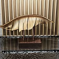 Golden Feather Sculpture with Intricate Carving Details on Black Textured Surface