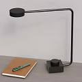 Modern Black Desk Lamp with Curved Arm on Wooden Tabletop with Notebook and Green Pen